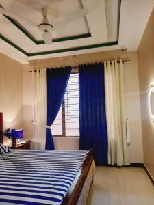 卡拉奇Dream home 2 & 4 bedroom Family house的一间卧室配有一张带蓝色窗帘的床和一扇窗户