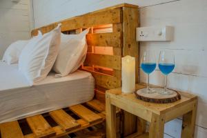 卡纳科纳The Pearl Beach Resort的一张睡床和一张桌子上的两杯蓝葡萄酒