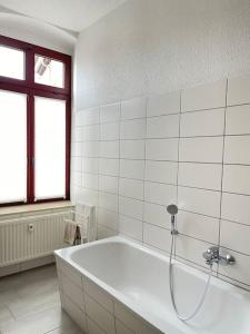 阿尔滕堡Moderne und stilvolle Wohnung direkt am Teich的白色的浴室设有浴缸和窗户。