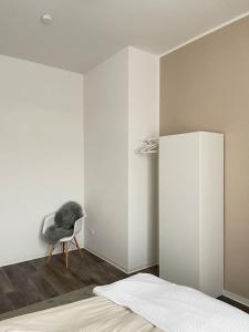 阿尔滕堡Moderne und stilvolle Wohnung direkt am Teich的一间卧室,卧室内配有一张床和一把椅子