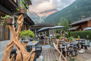 夏蒙尼-勃朗峰Eden Hotel, Apartments and Chalet Chamonix Les Praz的庭院配有桌椅,背景为山脉