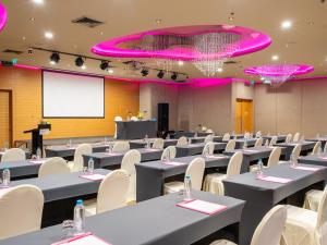 曼谷VELA Dhi GLOW Pratunam的一间会议室,配有桌椅和投影屏幕