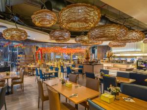 曼谷VELA Dhi GLOW Pratunam的餐厅设有桌椅和吊灯。