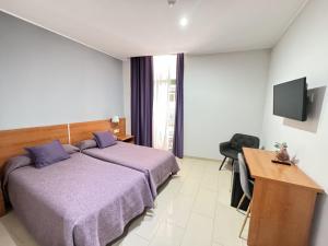 巴塞罗那加泰罗尼亚酒店的一间卧室配有一张床、一张书桌和一台电视