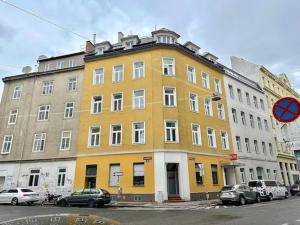 维也纳Designer Apartments Asaria的一座黄色的建筑,前面有汽车停放