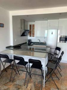 加的斯El Mirador de la Playa Cortadura Grupo AC Gestion的厨房配有白色的柜台和黑色的椅子