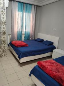 突尼斯Hotel Marhaba - Beb Bhar Tunis的一间卧室配有两张蓝色和红色床单
