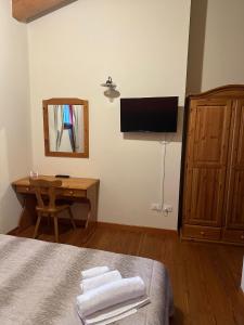 PolazzoLa corte dell'ulivo的一间卧室配有一张床、一张书桌和一台电视