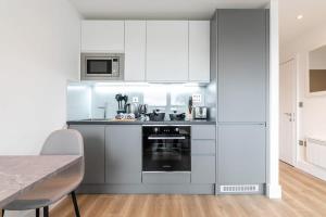东格林斯特德Bright and Modern Studio Apartment in East Grinstead的厨房配有白色橱柜和炉灶烤箱。