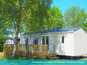 劳雷尔苏格Siblu camping Lauwersoog的白色的小房子,设有木甲板