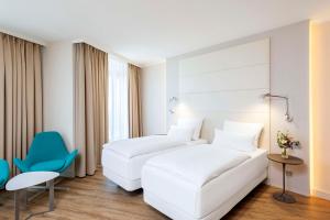 柏林NH酒店柏灵亚历山大广场店的酒店客房,设有两张床和一张蓝色椅子