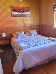 普尤瓦比港Cabañas Vientos del Sur en Puerto Puyuhuapi Aysen的卧室配有一张床铺,墙上挂着一棵树
