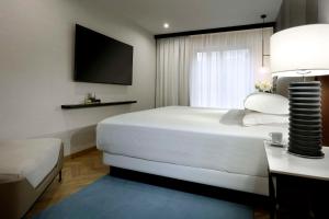 马德里Hyatt Regency Hesperia Madrid的卧室配有一张白色大床和电视。