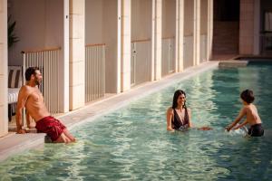 维拉摩拉Anantara Vilamoura Algarve Resort的一名男子和两名儿童在游泳池玩耍