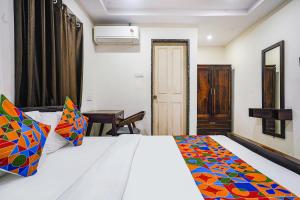 海得拉巴FabHotel Hamsa The Right Choice的卧室配有白色的床和色彩缤纷的毯子