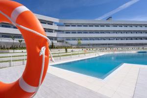 波苏埃洛-德阿拉尔孔Student Experience Madrid Pozuelo - Luxury Hostel的一座游泳池,在一座建筑前有一个橙色救生圈