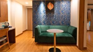 新德里The Orion Plaza - Nehru Place的客厅配有绿色沙发和桌子