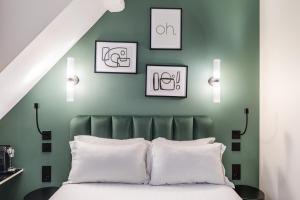 巴黎Hotel Elysée Secret的一间卧室设有绿色的墙壁和一张带白色枕头的床。