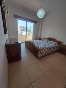 拉纳卡Sunny 2 Bedroom Larnaca Center的一间卧室配有一张床、一张桌子和一个窗户。