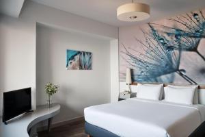 海若克利欧拉托精品酒店的卧室配有白色的床和电视