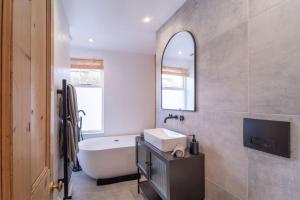 切尔滕纳姆Elegant 3 bedroom home in the centre of Cheltenham的带浴缸、水槽和镜子的浴室