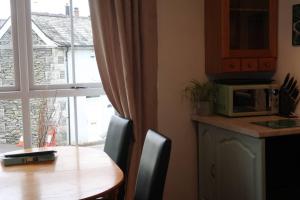 鲍内斯温德米尔Cosy 2-bedroom cottage in the Lake District的厨房配有桌子、微波炉和窗户。