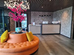 阿姆斯特丹Hotel Fogo Amsterdam的大堂设有橙色的沙发和带粉红色花卉的花瓶