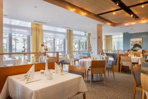 宾茨IFA吕根岛度假酒店的餐厅设有白色的桌椅和窗户。