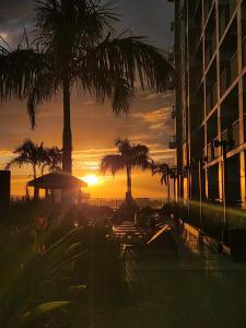 马尼拉SMDC Coast Residences near PICC World Trade Center MOA的落日,在一座建筑前,棕榈树成荫