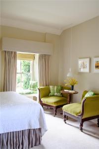 巴利瓦根Gregans Castle Hotel的一间卧室配有一张床、两把椅子和一个窗户