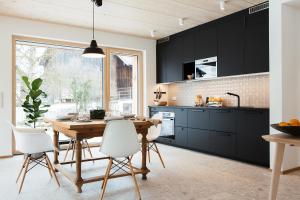 希明格Ferienhaus Schmidhuber的厨房配有黑色橱柜和木桌及椅子
