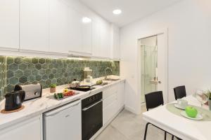 大加那利岛拉斯帕尔马斯Apartamentos Don Carlos的厨房配有白色橱柜、水槽和桌子