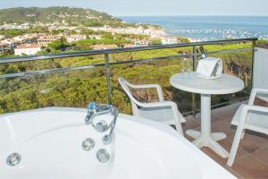 卡莱利亚德帕拉弗鲁赫尔加尔比酒店的阳台设有浴缸、桌子和椅子
