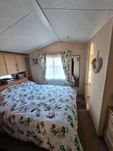 Lytchett MinsterSea Shore Chalet - Rockley Park的一间卧室配有一张带花卉床罩的床和窗户。