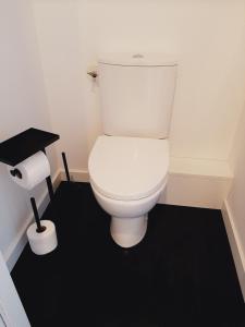 勒米尔蒙Chambre privée Au pied des Vosges的浴室铺有黑色地板,设有白色卫生间。