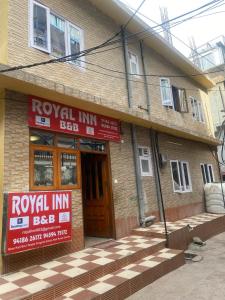 西姆拉BNB ROYAL INN SHIMLA的前面有皇家旅馆标志的建筑