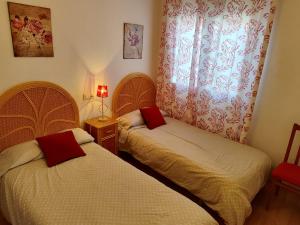 MembrillaSan Miguel的一间卧室设有两张床和红色窗帘