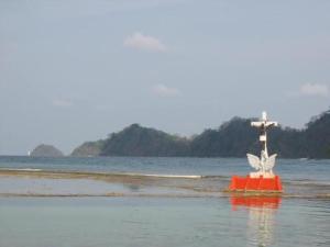 科隆Cabaña La Punta的一条红色的船,水中有一个十字架