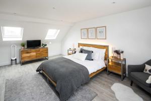 伦敦Contemporary 5 Bedroom with Garden North Finchley的一间卧室配有一张床、一台电视和一张沙发