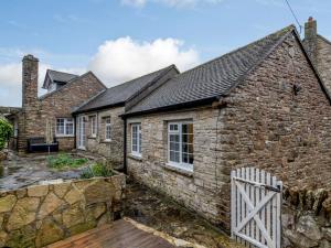 科夫堡3 Bed in Corfe Castle 81369的石头小屋前面设有白色的围栏