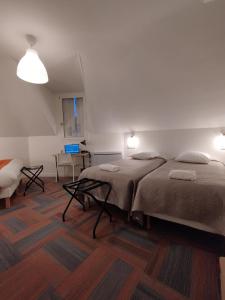 索米尔The Originals Access, Hotel Le Canter Saumur的一间卧室配有两张床、一张桌子和一把椅子