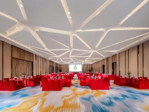 成都成都东部新区假日酒店的一个带红色椅子和屏幕的大型宴会厅