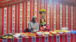瓦迪拉姆Wadi Rum albasli的坐在餐桌旁吃饭的男人和女人