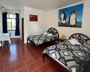 比亚米尔港Hotel Isla del descanso的墙上有两只企鹅的房间的两张床