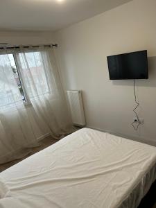 勒布朗-梅尼尔2 bedrooms proche Paris/CDG/Bourget/Parc des expo的卧室配有一张壁挂式平面电视的床。