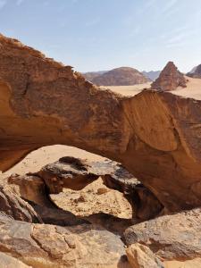 瓦迪拉姆wadi rum fox road camp & jeep tour的沙漠中的拱门,有山和岩石