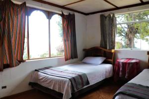 HuillanopampaINKA LAKE Taquile Lodge的一间小卧室,配有床和2个窗户