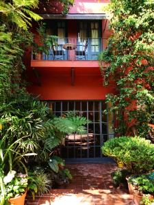 布宜诺斯艾利斯科波拉雅尔丹埃斯孔迪多比翼酒店的红色的建筑,阳台,配有椅子和植物