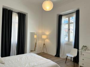 马拉加Suites Larios的一间卧室配有黑色窗帘、一张床和椅子
