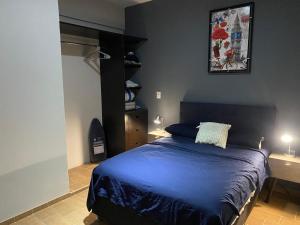 SayulaSayula luxury apartments的一间卧室配有一张带蓝色床单和两盏灯的床。